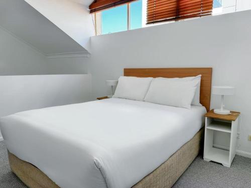 a white bed in a small room with a window at Bridgewater Rivercity in Brisbane