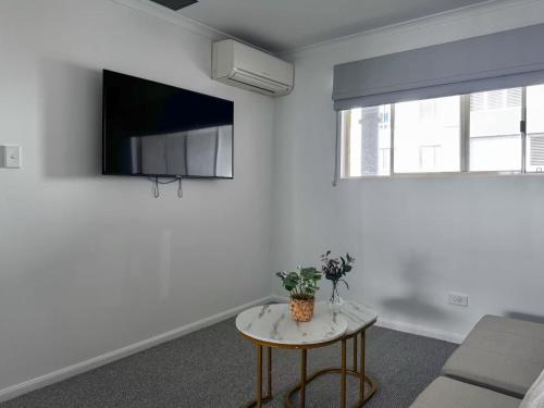 a white living room with a table and a tv at Bridgewater Rivercity in Brisbane