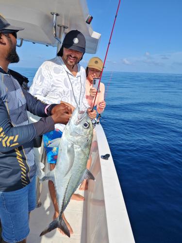 a man holding a fish on a boat at Blue Wave Hotel Maldives in Kudahuvadhoo