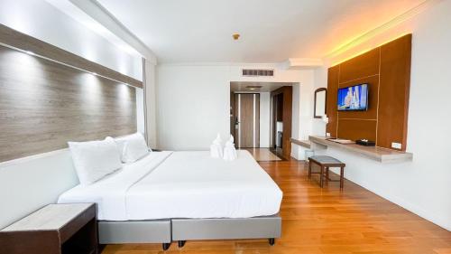 a bedroom with a large white bed and a tv at Thong Tarin Hotel in Surin