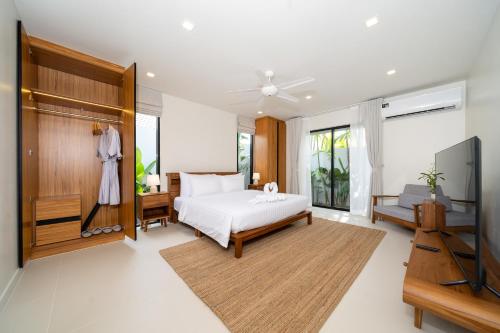 Un dormitorio con una cama y un televisor de pantalla plana. en Anchan Villas Phuket - 4 BR Signature Pool Villa by Escape Villas, en Ban Phru Champa