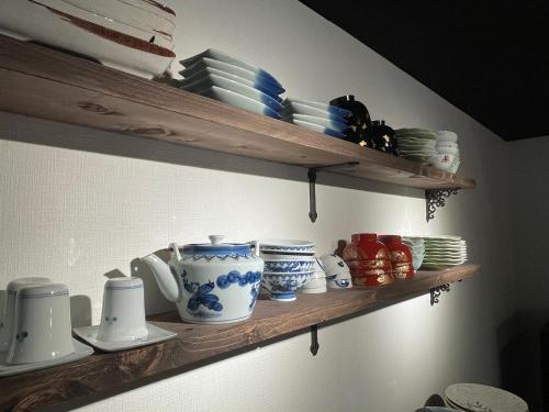 a shelf with plates and cups and dishes on it at TAKUMI-AN Private Ancient House and Garden in Numazu