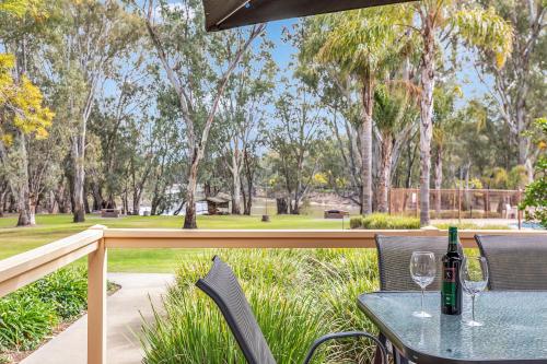 a table with two glasses of wine on a balcony at Riverfront Escape - Pool Fun and Space for Everyone in Moama