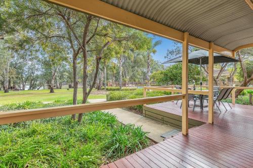 an outdoor deck with a table and an umbrella at Riverfront Escape - Pool Fun and Space for Everyone in Moama