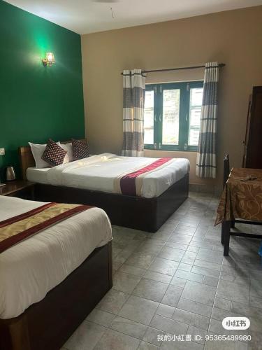 a bedroom with two beds and a green wall at Hotel Horizon Homes - Sauraha Chitwan in Sauraha