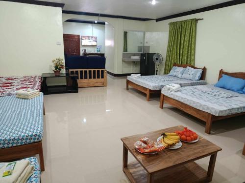 a living room with two beds and a table with a bowl of fruit at Balai Mariacaria Pension House in Guindulman