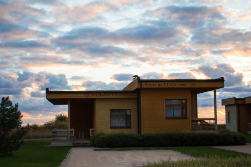 a small building with a cloudy sky in the background at Kapteinu Osta in Salacgrīva