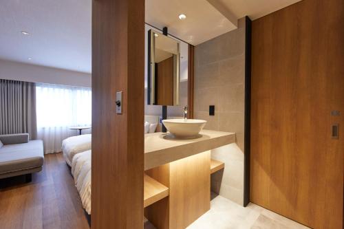 a bathroom with a sink and a bed in a room at Hotel Stelle Belle in Hakuba