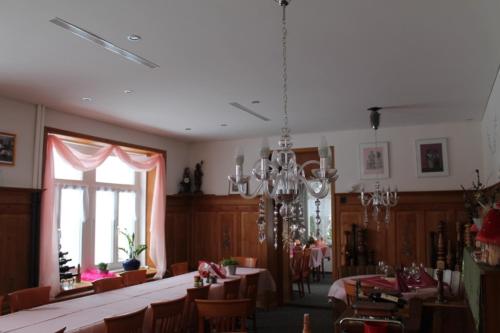 una sala da pranzo con tavoli, sedie e lampadario a braccio di Hotel Restaurant Belvedere a Weissbad