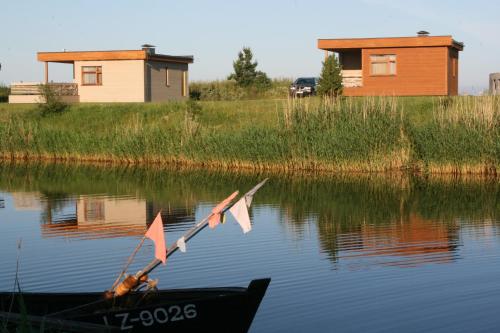 a boat in the water with a house in the background at Kapteinu Osta in Salacgrīva
