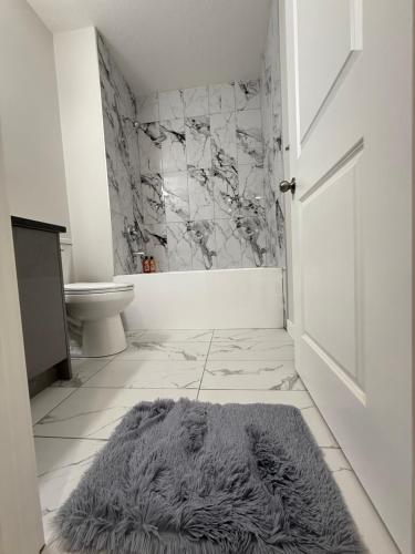 a bathroom with a rug on the floor and a toilet at Super house in Calgary