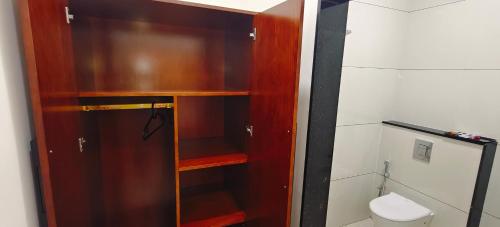 a bathroom with a toilet and a wooden cabinet at Aswin Residency in Nāmakkal