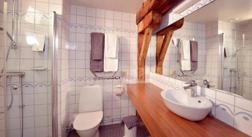 a white bathroom with a sink and a toilet at Clarion Collection Hotel Packhuset in Kalmar