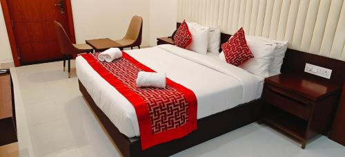 a bedroom with a bed with a red blanket and a chair at Aswin Residency in Nāmakkal