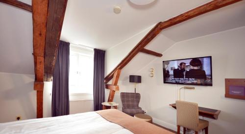 a bedroom with a bed and a tv on the wall at Home Hotel Packhuset in Kalmar