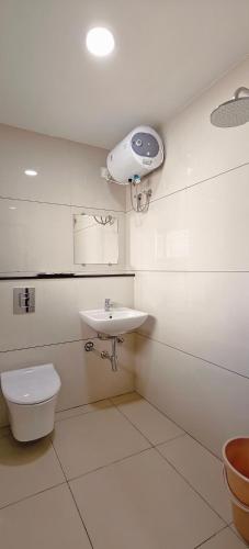 a bathroom with a toilet and a sink and a light at Aswin Residency in Nāmakkal