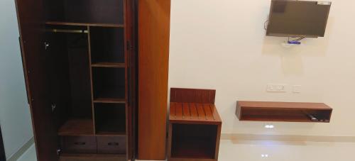 a room with a tv and a wooden cabinet at Aswin Residency in Nāmakkal