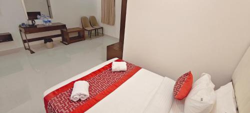 a bedroom with a bed with towels and a desk at Aswin Residency in Nāmakkal