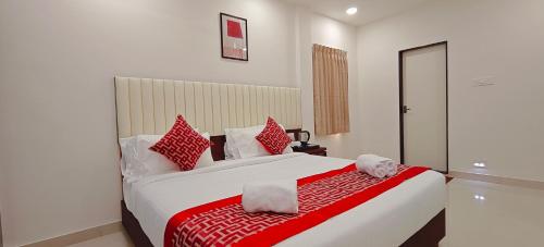 a bedroom with a large bed with red and white pillows at Aswin Residency in Nāmakkal