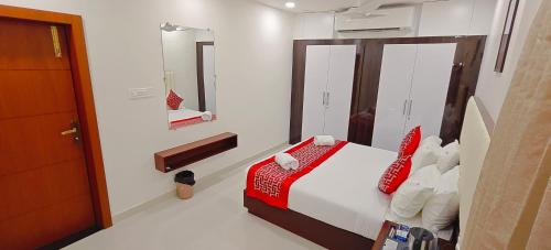 a bedroom with a bed with red pillows and a mirror at Aswin Residency in Nāmakkal