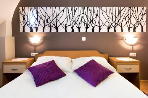 a bedroom with a bed with two purple pillows at Rooms & Apartments Kepic, AIRPORT accomodation in Cerklje na Gorenjskem