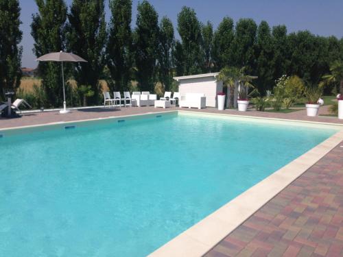 a large blue swimming pool with an umbrella at Hotel Bussana in Porto Tolle