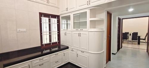 a kitchen with white cabinets and a dining room at Aswin Residency in Nāmakkal