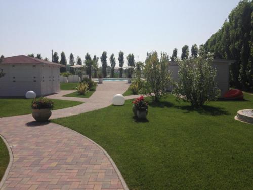 a brick walkway in a yard with bushes and trees at Hotel Bussana in Porto Tolle
