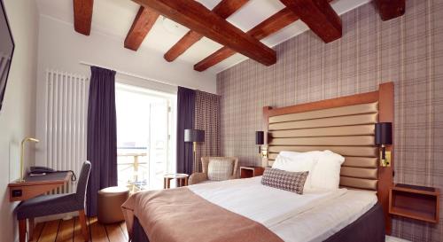 a bedroom with a bed and a desk and a window at Home Hotel Packhuset in Kalmar