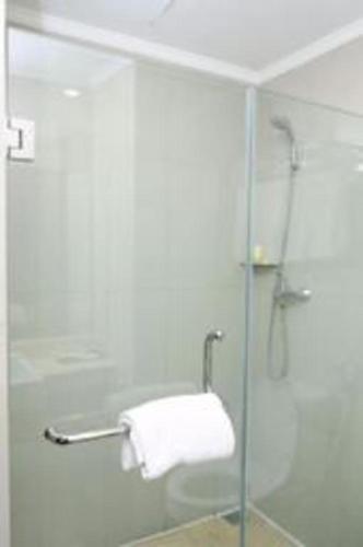 a shower with a glass door and a towel at Asialink Premier in Karawang