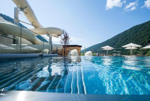 a swimming pool with blue water and umbrellas at Familienhotel Huber in Valles
