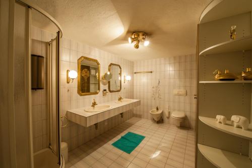 ein Badezimmer mit einem Waschbecken, einem WC und einem Spiegel in der Unterkunft Appartements Al Castagno in Ehrwald