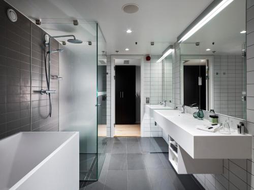 a bathroom with two sinks and a shower and a mirror at Gothia Towers & Upper House in Gothenburg