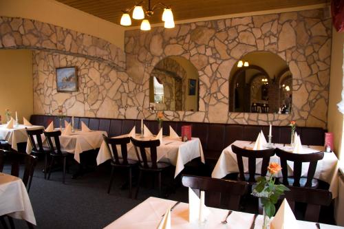 a dining room with tables and chairs and a stone wall at Hotel Rendsburg in Rendsburg