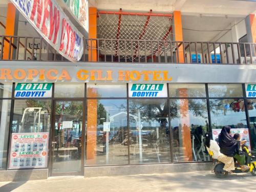 a person riding a scooter in front of a store at Tropica Gili Hotel - Free Access Gym and Coworking Space in Gili Trawangan
