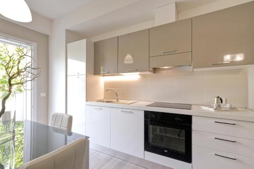 a kitchen with white cabinets and a sink and an oven at Residence Armony in Misano Adriatico