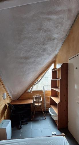 an attic room with a desk and a chair at Charmant petit chalet dans la forêt in Gesves