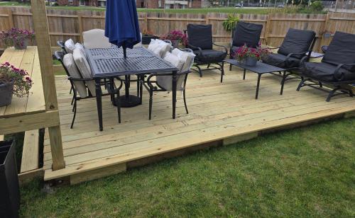 a wooden deck with chairs and a table and umbrella at Luxx Guest House in Milwaukee