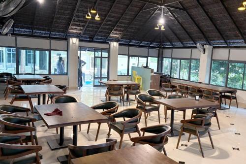 a cafeteria with wooden tables and chairs and windows at The REEF LOUNGE in Mandya