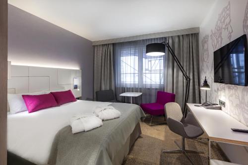 a hotel room with a large bed and a desk at Mercure Krakow Stare Miasto in Kraków