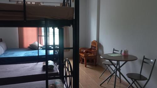 a room with a bunk bed and a table and chair at Amaretto Hostel in Surat Thani