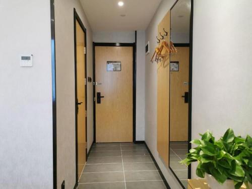 a hallway with three doors and a potted plant at GreenTree Inn Ganzhou Gan County Bus Station in Ganzhou