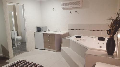 a bathroom with a tub and a sink and a toilet at Coastal Bay Motel in Coffs Harbour