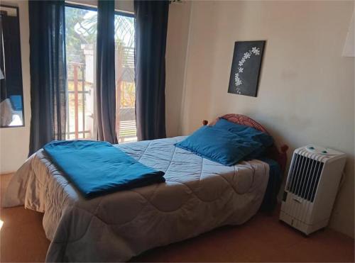 a bedroom with a bed with blue pillows and a window at Nomad's Nest in Lusaka