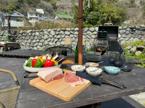 a table with a plate of meat and a bowl of vegetables at TAKUMI-AN Private Ancient House and Garden in Numazu