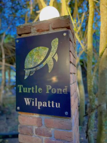 a sign for a turtle pond willricular on a brick wall at Turtle Pond Wilpattu in Wilpattu
