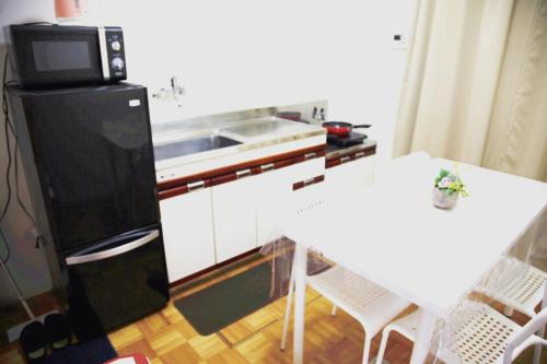 a kitchen with a refrigerator and a table with a microwave at Sweet House東池袋 in Tokyo