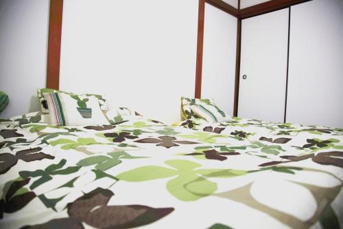 a bed with a green and white comforter at Sweet House東池袋 in Tokyo