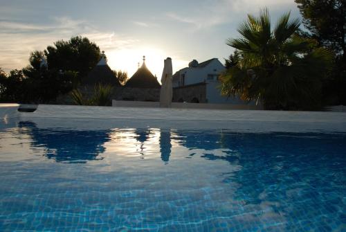 a swimming pool in front of a house with the sunset at Masseria Battaglini in Martina Franca