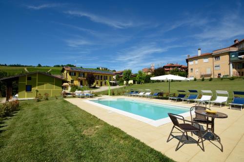 a swimming pool in a yard with chairs and a table at The Green Guest House in Barolo